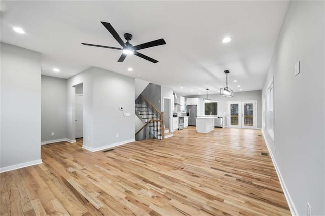 unfurnished living room featuring stairs, light wood-style flooring, and recessed lighting