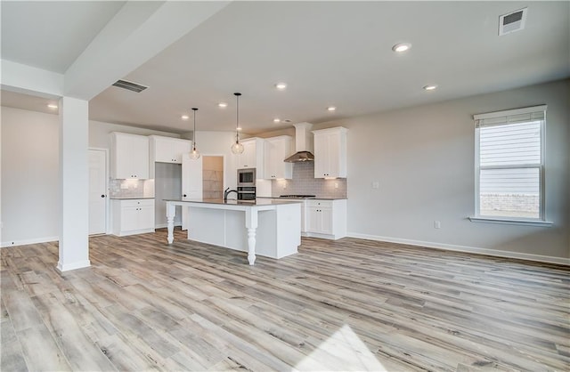 512 Dolce Rd, Locust Grove, GA 30248 - kitchen featuring wall chimney range hood, a breakfast bar, visible vents, light wood-style flooring, and decorative backsplash