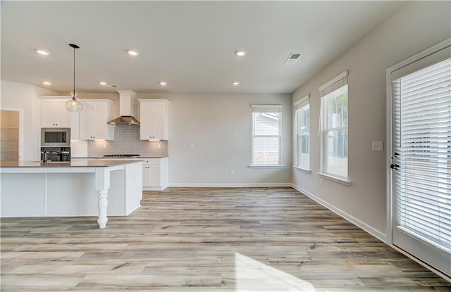 512 Dolce Rd, Locust Grove, GA 30248 - kitchen featuring tasteful backsplash, visible vents, wall chimney exhaust hood, white cabinetry, and appliances with stainless steel finishes