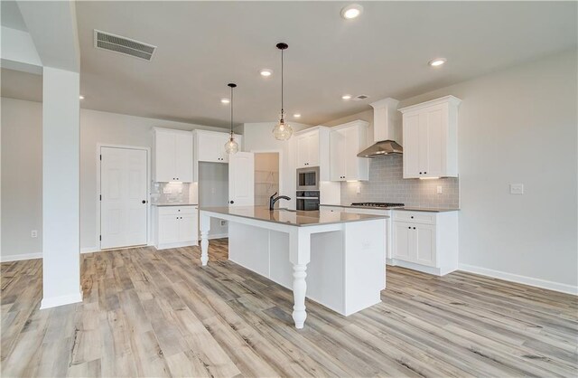 512 Dolce Rd, Locust Grove, GA 30248 - kitchen featuring stainless steel appliances, visible vents, wall chimney exhaust hood, an island with sink, and decorative backsplash
