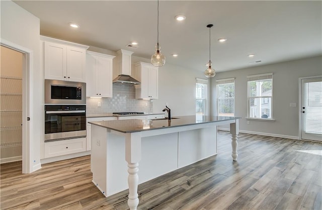 512 Dolce Rd, Locust Grove, GA 30248 - kitchen with light wood-style flooring, an island with sink, a sink, wall chimney exhaust hood, and stainless steel appliances