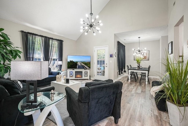 living room featuring high vaulted ceiling, a chandelier, and light hardwood / wood-style floors