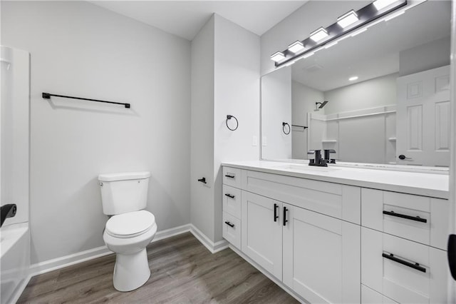 full bath featuring baseboards, wood finished floors, toilet, and vanity