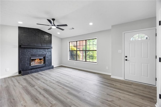 unfurnished living room with ceiling fan, visible vents, wood finished floors, and a fireplace