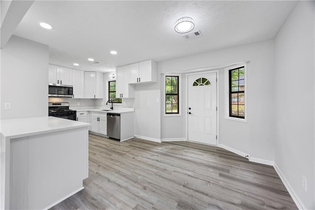 kitchen with baseboards, white cabinets, stainless steel appliances, and visible vents