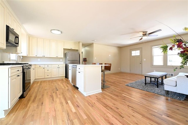 kitchen with light wood-type flooring, appliances with stainless steel finishes, a breakfast bar, and a center island