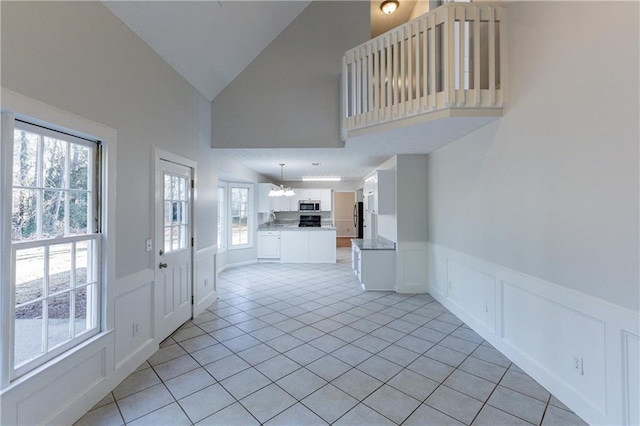 tiled entrance foyer featuring vaulted ceiling and a notable chandelier