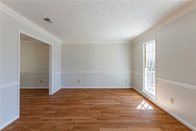 empty room with hardwood / wood-style floors, ornamental molding, and a textured ceiling