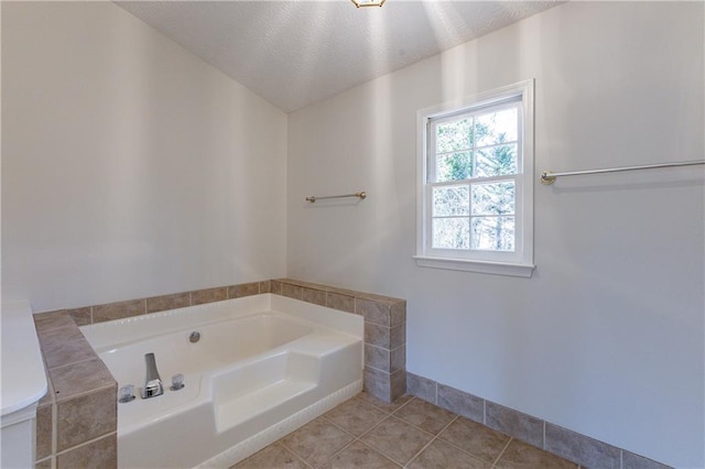 bathroom featuring tile patterned flooring, a washtub, and a textured ceiling