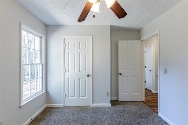 unfurnished bedroom featuring ceiling fan, dark carpet, and a textured ceiling