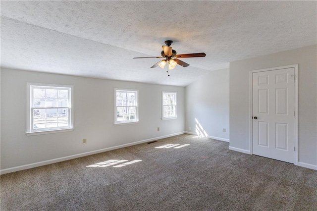 spare room with vaulted ceiling, ceiling fan, carpet floors, and a textured ceiling