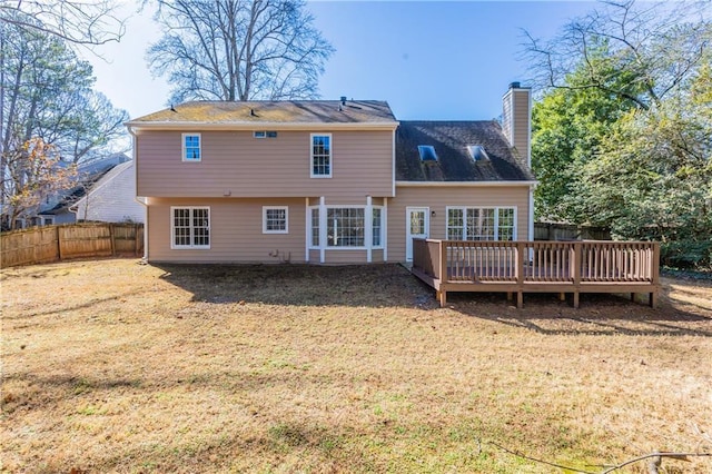 rear view of house featuring a wooden deck and a lawn