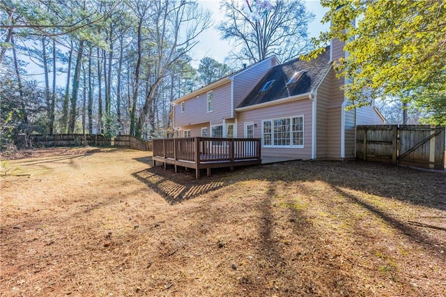 rear view of property featuring a wooden deck and a lawn