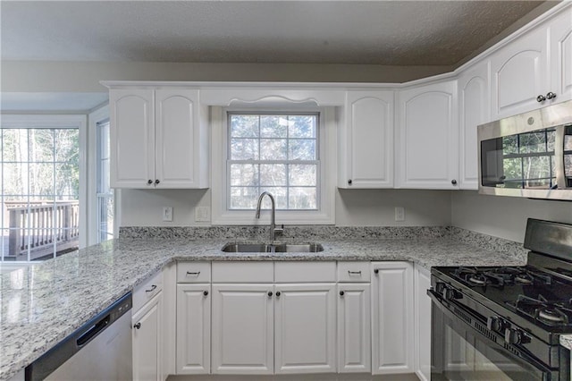 kitchen with white cabinetry, sink, light stone counters, and stainless steel appliances