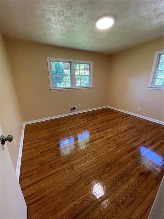 empty room featuring a textured ceiling and wood-type flooring