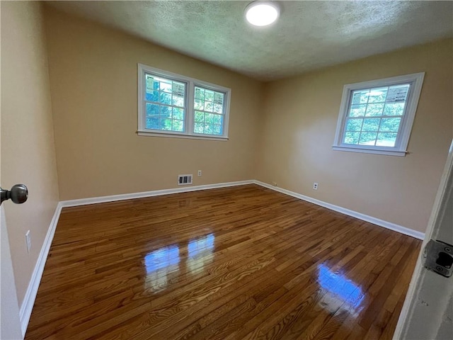 unfurnished room with hardwood / wood-style flooring and a textured ceiling