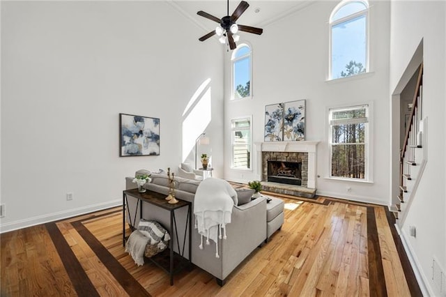 224 Celestial Ridge Dr, Dallas, GA 30132 - living room featuring wood-type flooring, stairs, a towering ceiling, a stone fireplace, and a ceiling fan