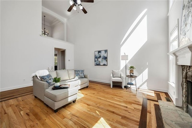 224 Celestial Ridge Dr, Dallas, GA 30132 - living area with a high ceiling, a stone fireplace, a ceiling fan, light wood-style flooring, and a chandelier