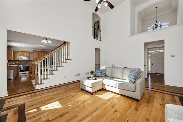 224 Celestial Ridge Dr, Dallas, GA 30132 - living room with a chandelier, light wood finished floors, a high ceiling, stairway, and ornamental molding