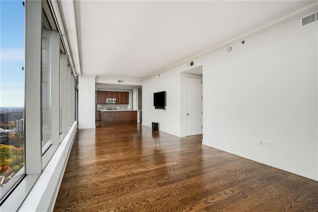 unfurnished living room featuring crown molding and dark wood-type flooring