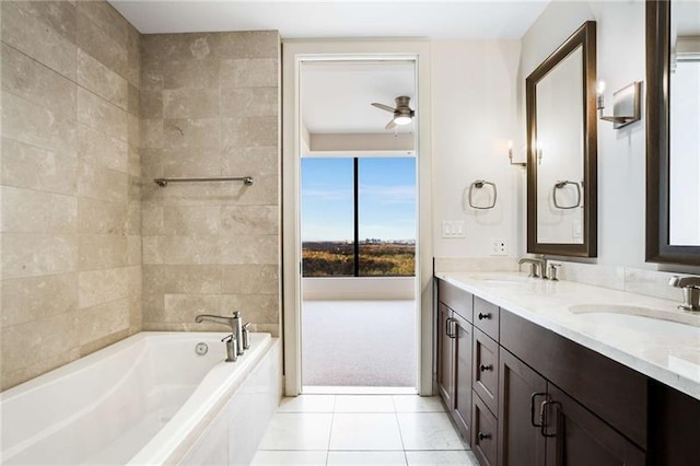 bathroom with tile patterned flooring, vanity, tiled bath, and ceiling fan