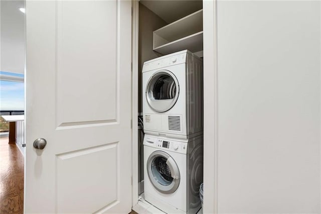 laundry area featuring wood-type flooring and stacked washer and clothes dryer