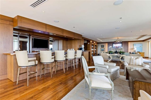 living room featuring a tray ceiling, light hardwood / wood-style flooring, and a wealth of natural light