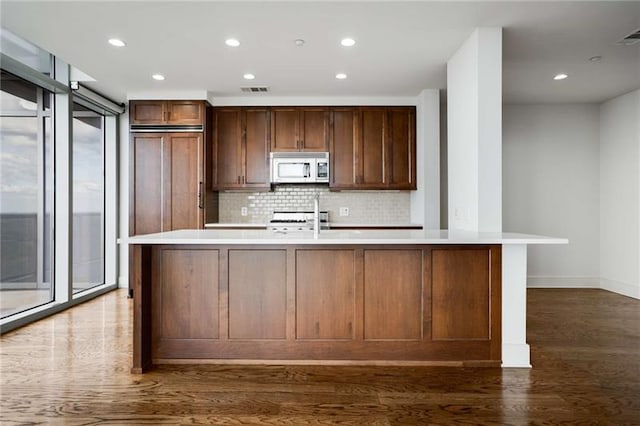 kitchen with dark hardwood / wood-style floors, plenty of natural light, and a kitchen island with sink