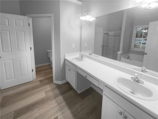 bathroom with toilet, a shower stall, a sink, and wood finished floors