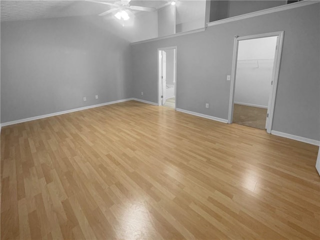 spare room featuring high vaulted ceiling, light wood-style floors, baseboards, and a ceiling fan