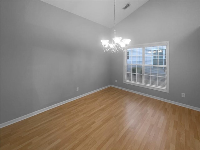 spare room featuring light wood-style floors, baseboards, and a notable chandelier