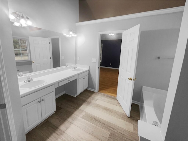 full bath with double vanity, a sink, a bath, and wood finished floors