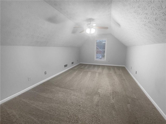 additional living space featuring a textured ceiling, carpet floors, a ceiling fan, baseboards, and vaulted ceiling