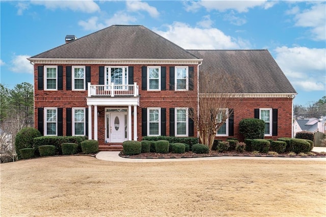 colonial house featuring a front lawn and a balcony