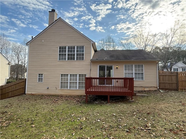 back of property with a chimney, a fenced backyard, a yard, and a deck