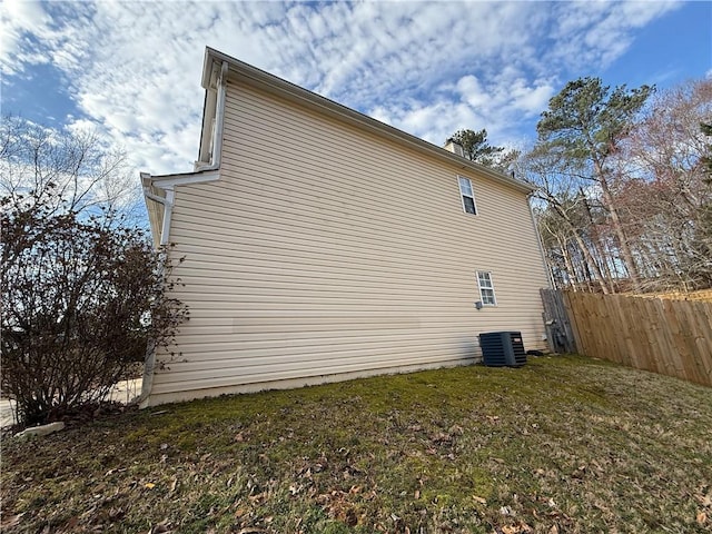 view of side of home featuring a lawn, fence, and central air condition unit