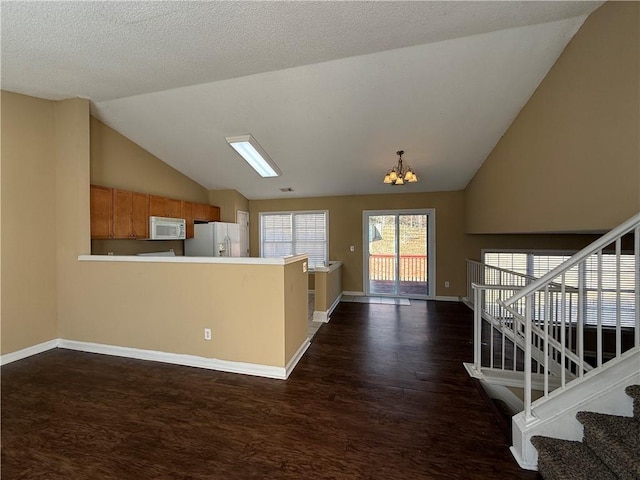 kitchen featuring white appliances, baseboards, dark wood-type flooring, an inviting chandelier, and vaulted ceiling