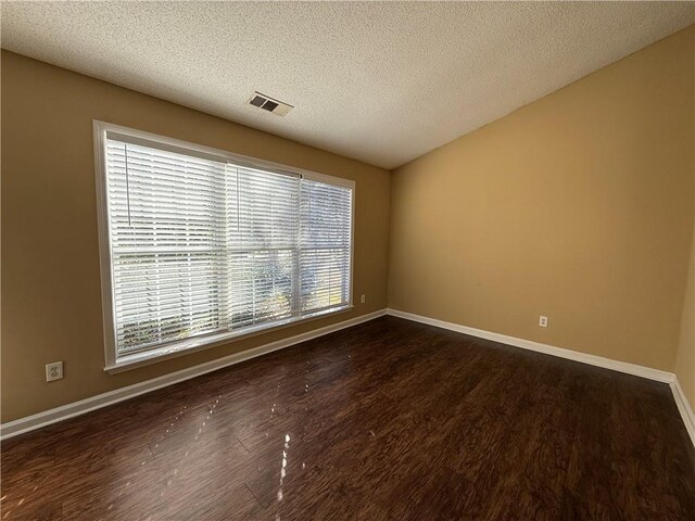 unfurnished room with baseboards, visible vents, and dark wood finished floors