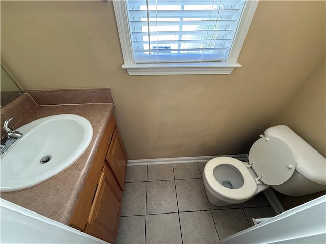 half bath with toilet, tile patterned flooring, vanity, and baseboards