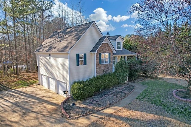 view of side of home with a garage, stone siding, and driveway