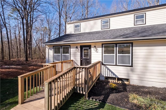 view of front of property featuring a shingled roof and a wooden deck