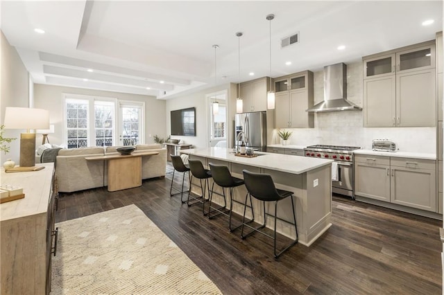 kitchen with visible vents, decorative backsplash, appliances with stainless steel finishes, wall chimney range hood, and open floor plan