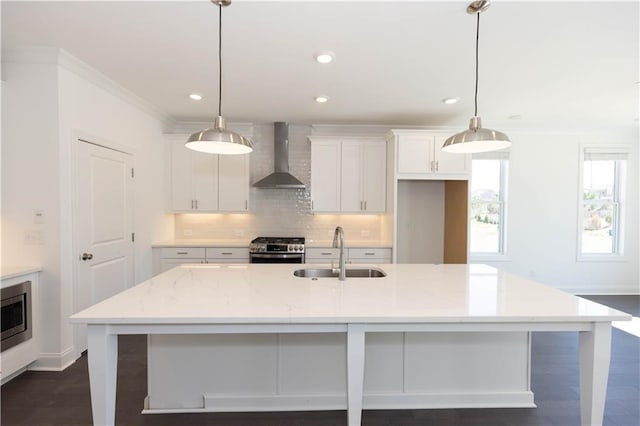 kitchen featuring stainless steel appliances, decorative light fixtures, sink, and wall chimney range hood