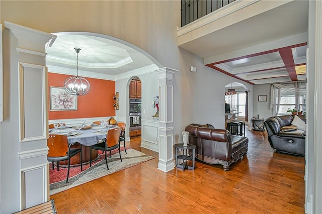 dining space with coffered ceiling, decorative columns, a chandelier, light hardwood / wood-style floors, and ornamental molding