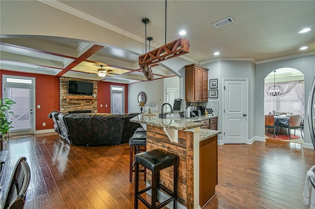 kitchen featuring pendant lighting, coffered ceiling, ceiling fan with notable chandelier, light stone counters, and dark hardwood / wood-style flooring