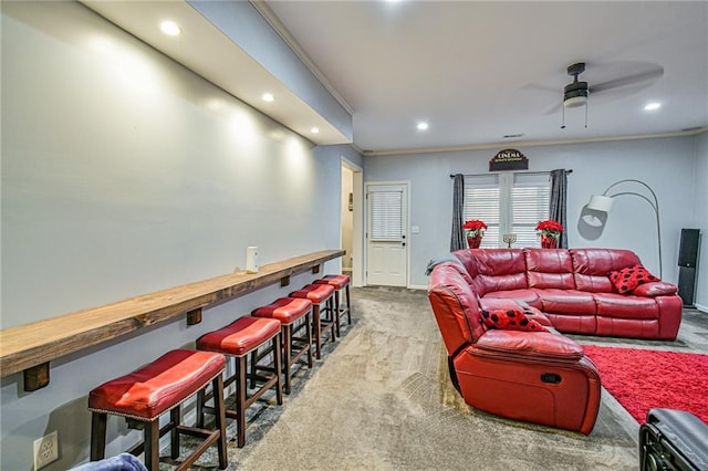 carpeted living room featuring ceiling fan, crown molding, and bar area