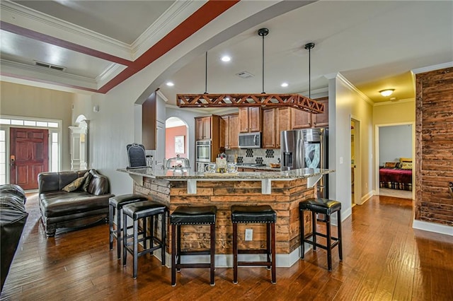 kitchen with pendant lighting, crown molding, dark hardwood / wood-style floors, light stone counters, and stainless steel appliances