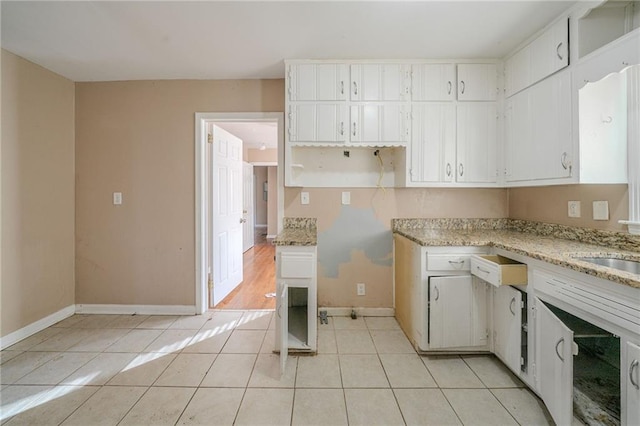 kitchen featuring light stone countertops, white cabinets, and light tile patterned flooring