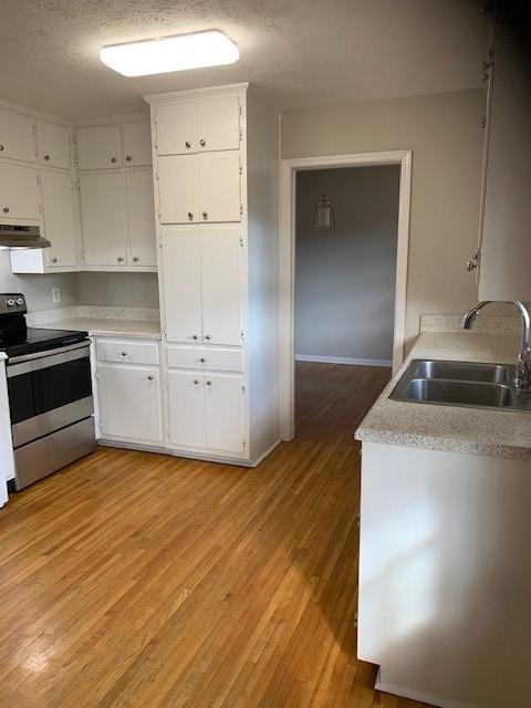 kitchen featuring white cabinetry, electric stove, sink, and light hardwood / wood-style flooring