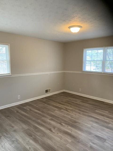 spare room featuring dark hardwood / wood-style floors and a textured ceiling